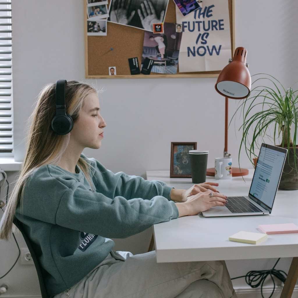A woman using a laptop and headphones in a cozy workspace, highlighting supportive tools for working with autism