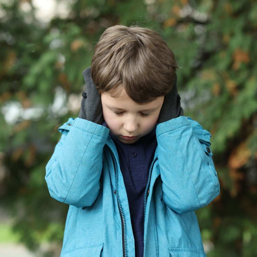 A young child swith hands over their ears, showing how different autism levels can affect sensory comfort.