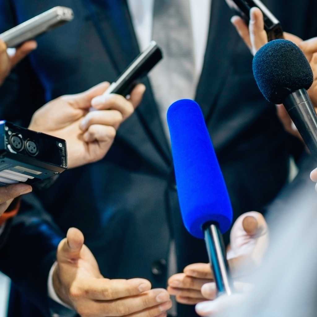Reporters holding microphones and recorders during a press interview