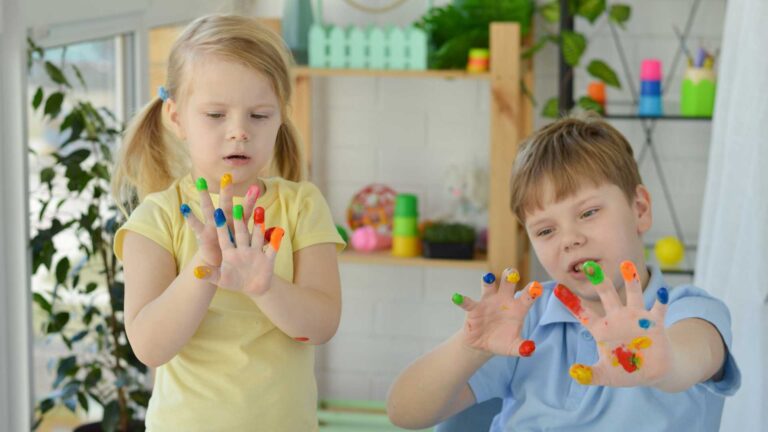 Children exploring sensory play with colorful paint on their hands, representing sensory processing disorder and autism spectrum disorder