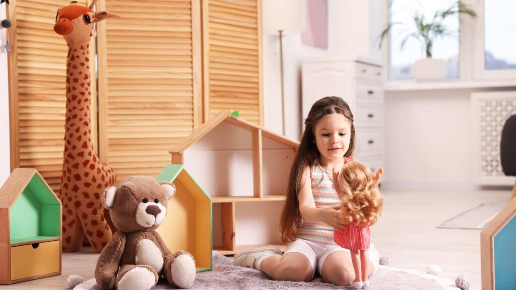 Young child sitting on the floor playing with a doll.