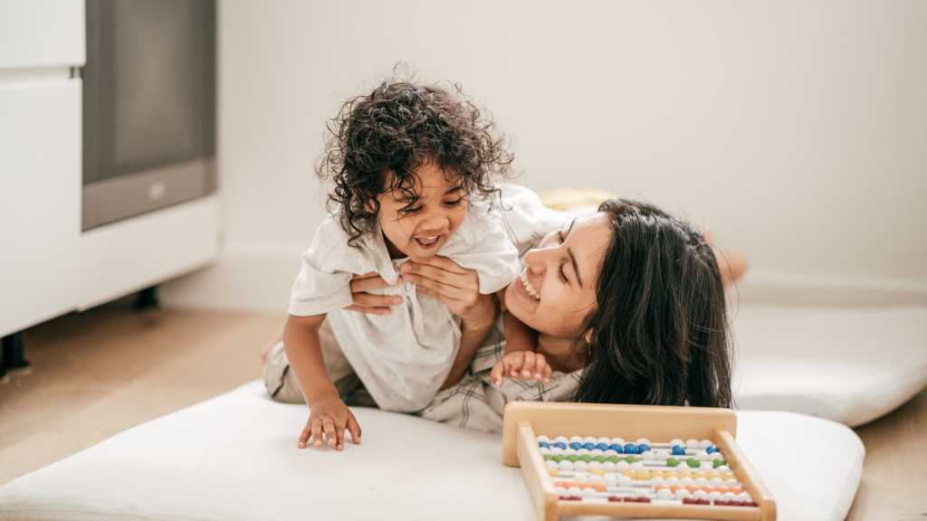 Parent playing with toddler, responding to name milestone and social bonding